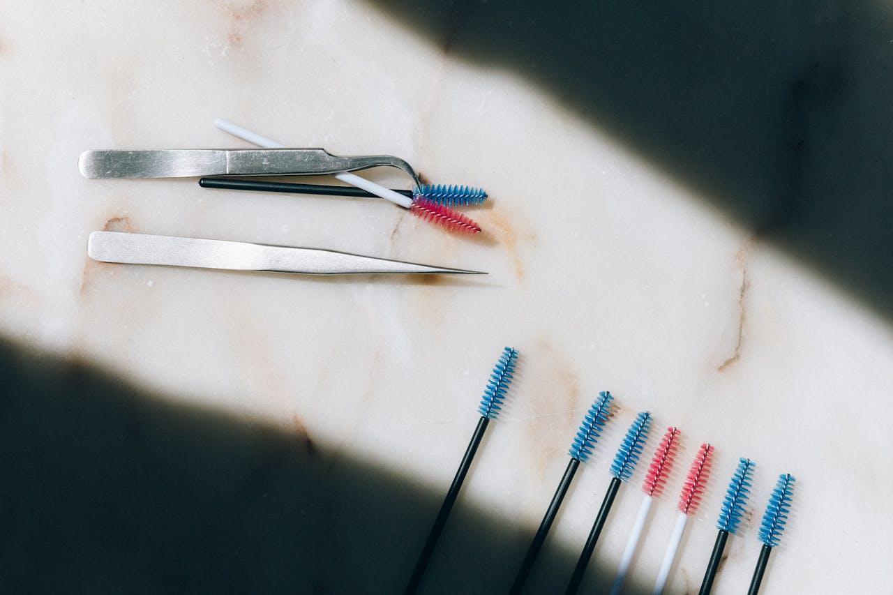 Colorful eyelash brushes and tweezers on a marble surface. Perfect for beauty and cosmetic themes.